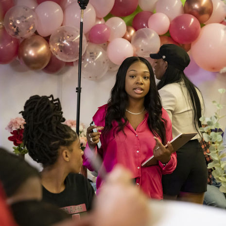  Image of Jaida Ragland  wearing a pink blouse and standing in front of balloons 