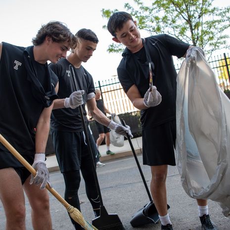 Image of men's soccer players cleaning up the area near Temple Sports Complex.